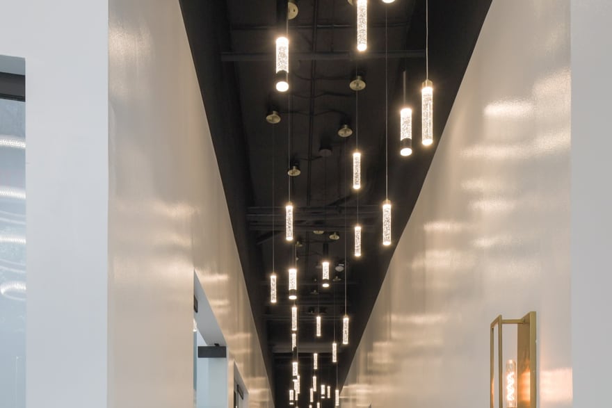 The suite corridor at the Bethesda building: a run of doors under a line of pendant lights, reflected in a polished calacatta floor.