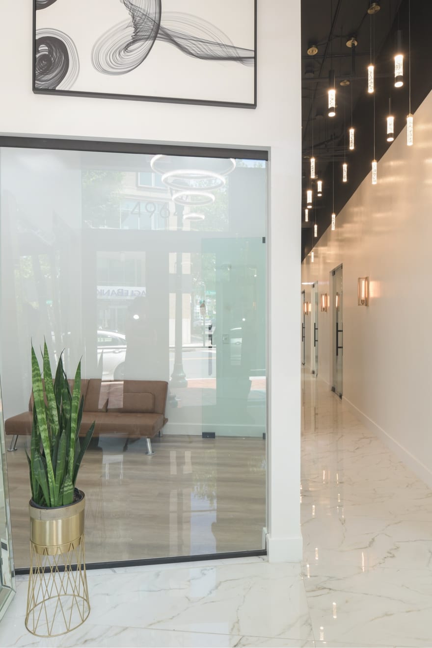 The glazed entrance at the Bethesda building, looking in through full-height glass doors to the lit reception and the suite corridor beyond.